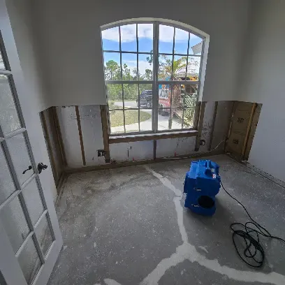 Air mover drying a flood-cut room with arched windows in a Venice, FL home